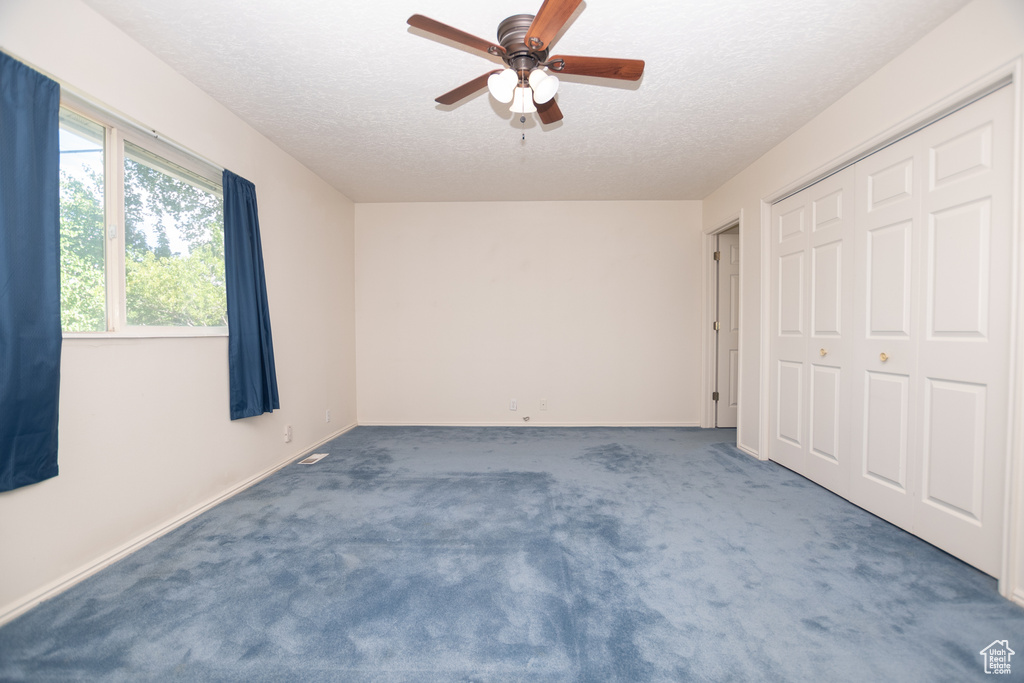 Unfurnished bedroom featuring a textured ceiling, carpet, a closet, and ceiling fan