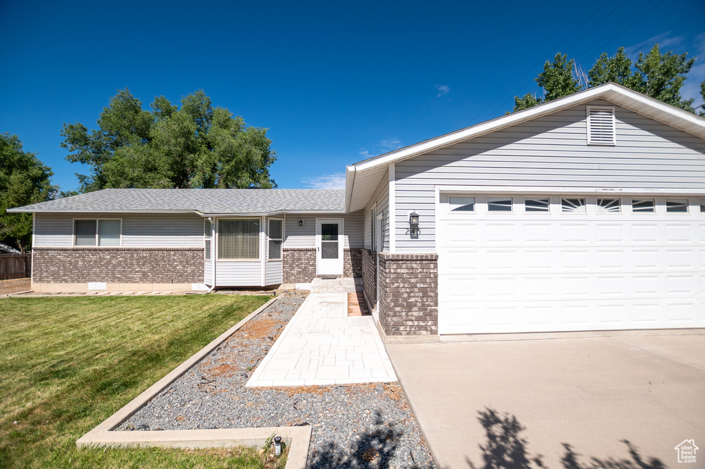Ranch-style home featuring brick siding, a front yard, a garage, and driveway