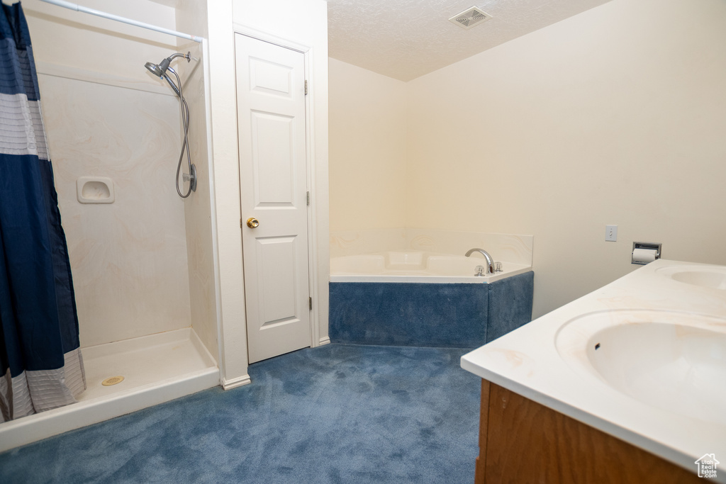 Bathroom with a shower with curtain, a garden tub, double vanity, and a textured ceiling