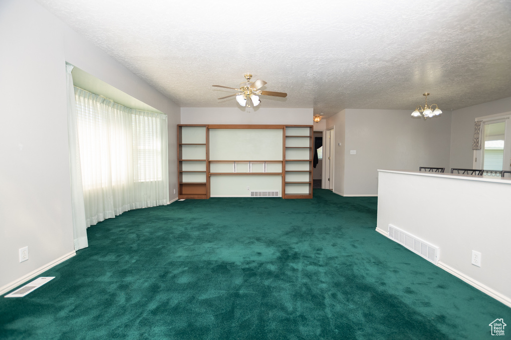 Unfurnished living room featuring a chandelier, ceiling fan, a textured ceiling, and carpet