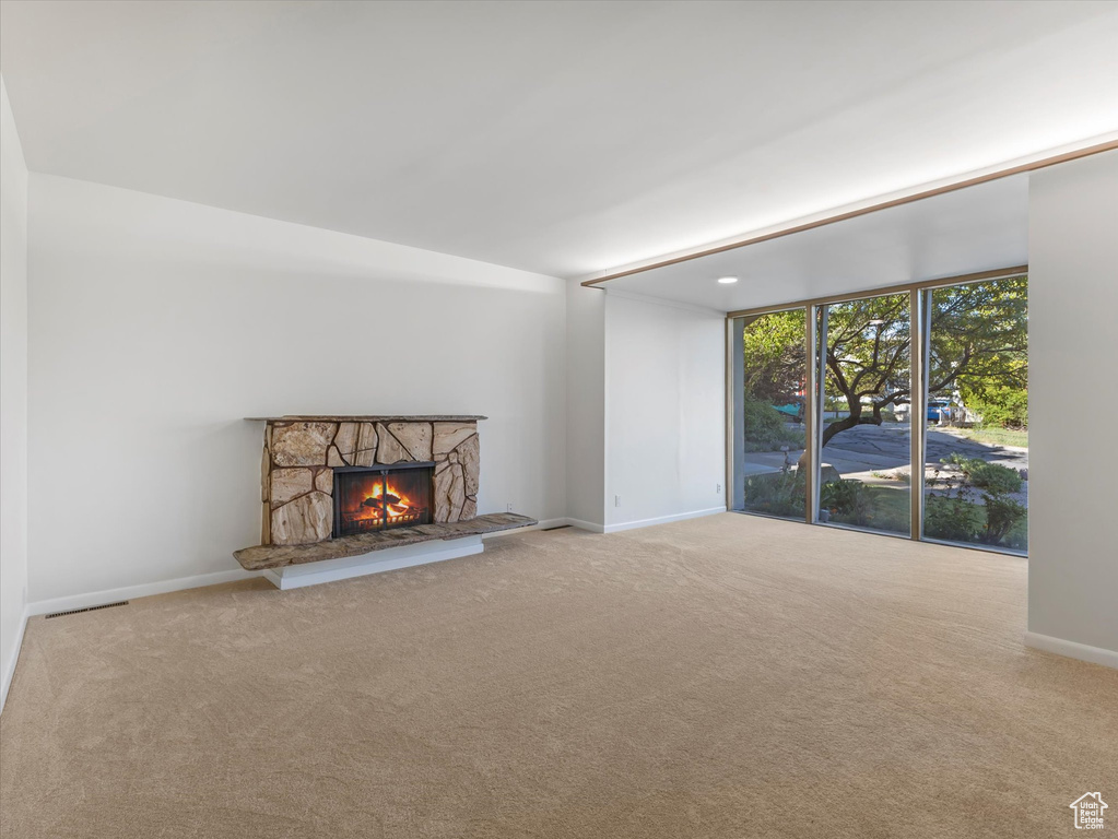 Unfurnished living room with a fireplace, carpet floors, and baseboards