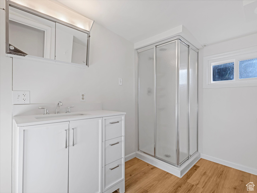 Full bath with a stall shower, wood finished floors, baseboards, and vanity