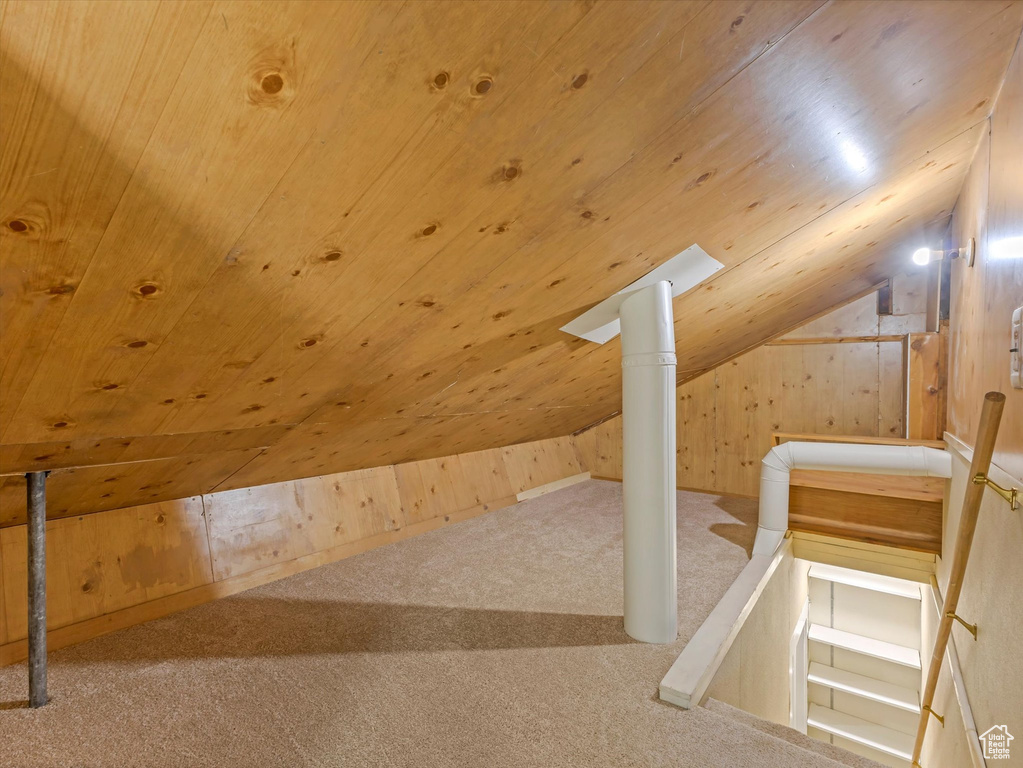 Additional living space featuring carpet flooring, vaulted ceiling, wooden ceiling, and wooden walls