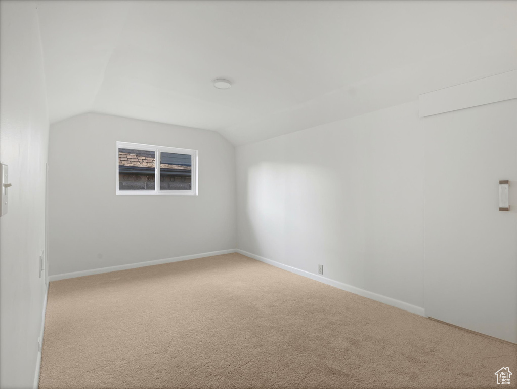 Spare room with carpet floors, vaulted ceiling, and baseboards