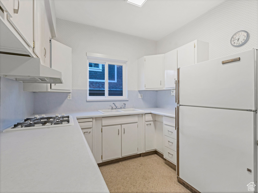 Kitchen featuring white appliances, a sink, light countertops, and white cabinets