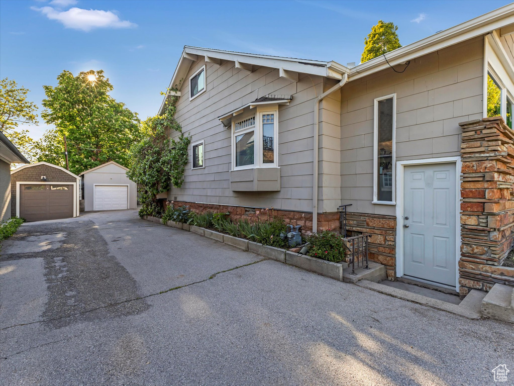 View of side of property featuring a detached garage, an outdoor structure, and asphalt driveway