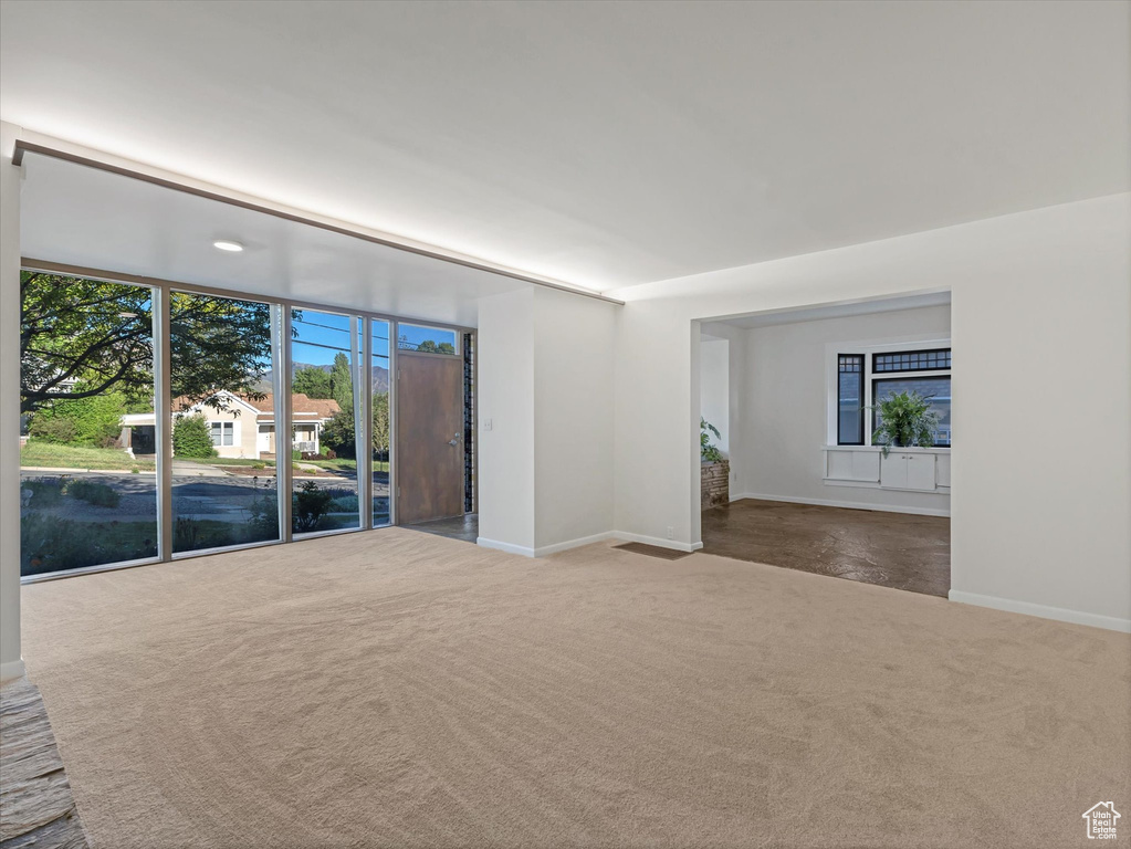 Carpeted spare room featuring baseboards