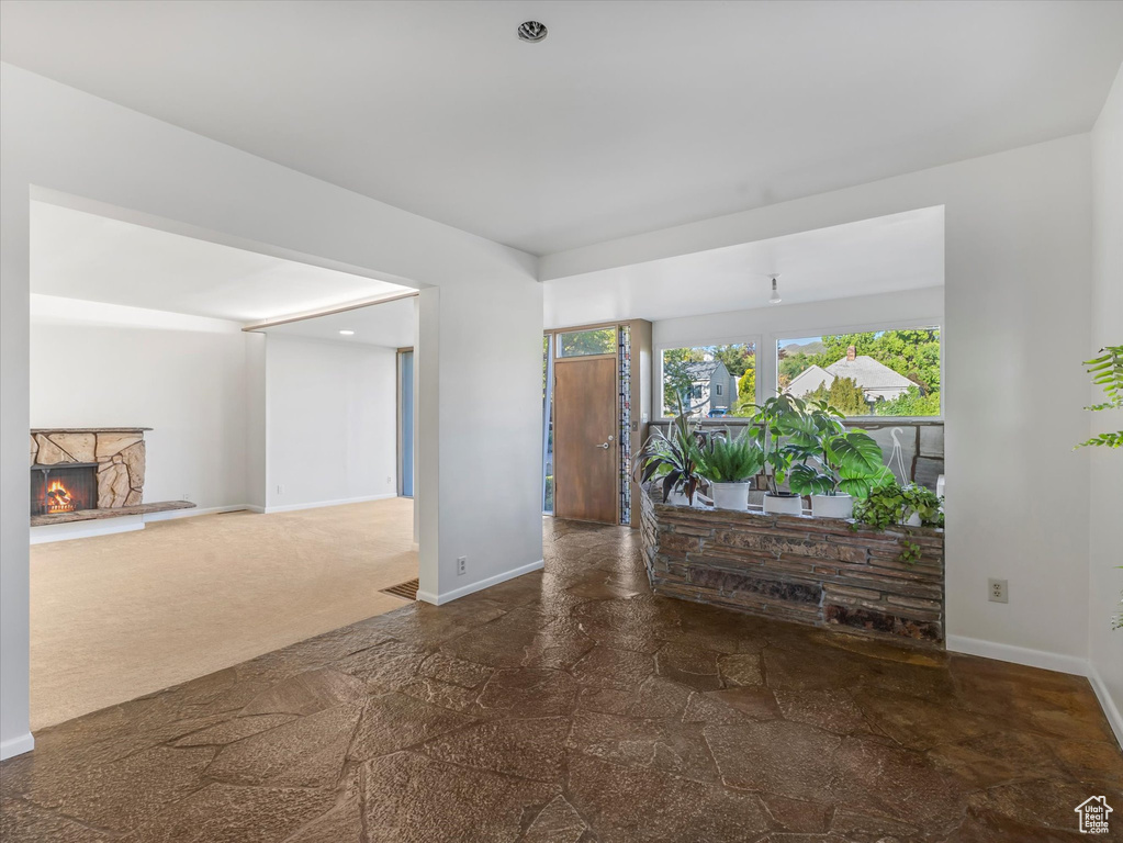 Unfurnished room with stone finish floors, baseboards, and a lit fireplace