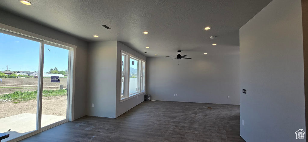 Spare room featuring healthy amount of natural light, recessed lighting, a ceiling fan, a textured ceiling, and wood finished floors