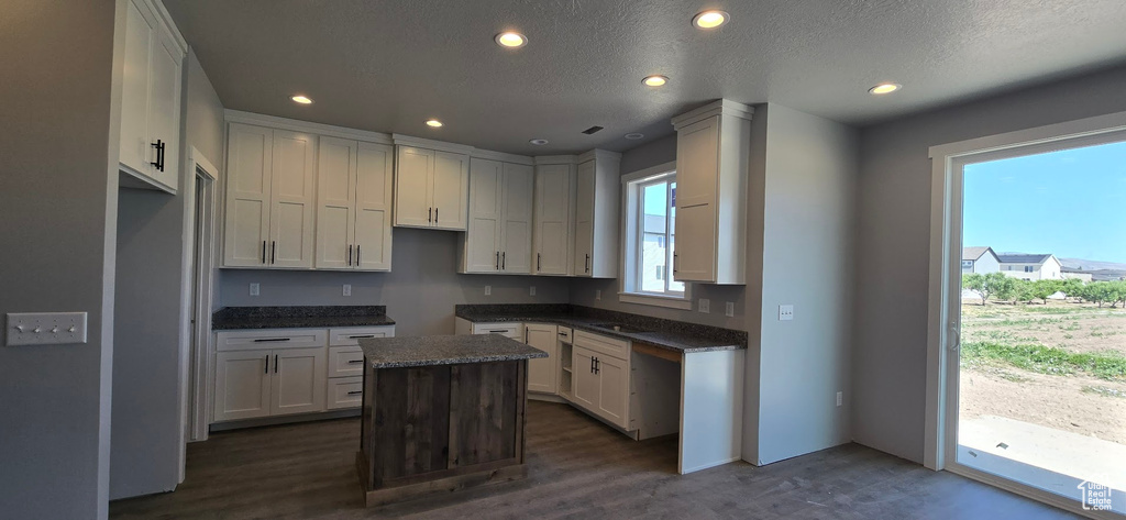 Kitchen featuring a center island, recessed lighting, dark wood finished floors, dark countertops, and a textured ceiling
