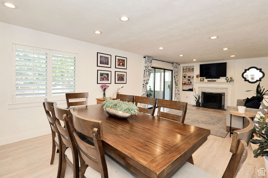 Dining area featuring recessed lighting, light wood-style flooring, a fireplace, and baseboards