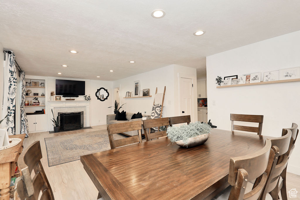 Dining space with a fireplace with flush hearth, recessed lighting, and light wood finished floors