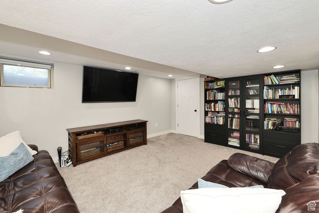 Carpeted living area featuring a textured ceiling, recessed lighting, and baseboards