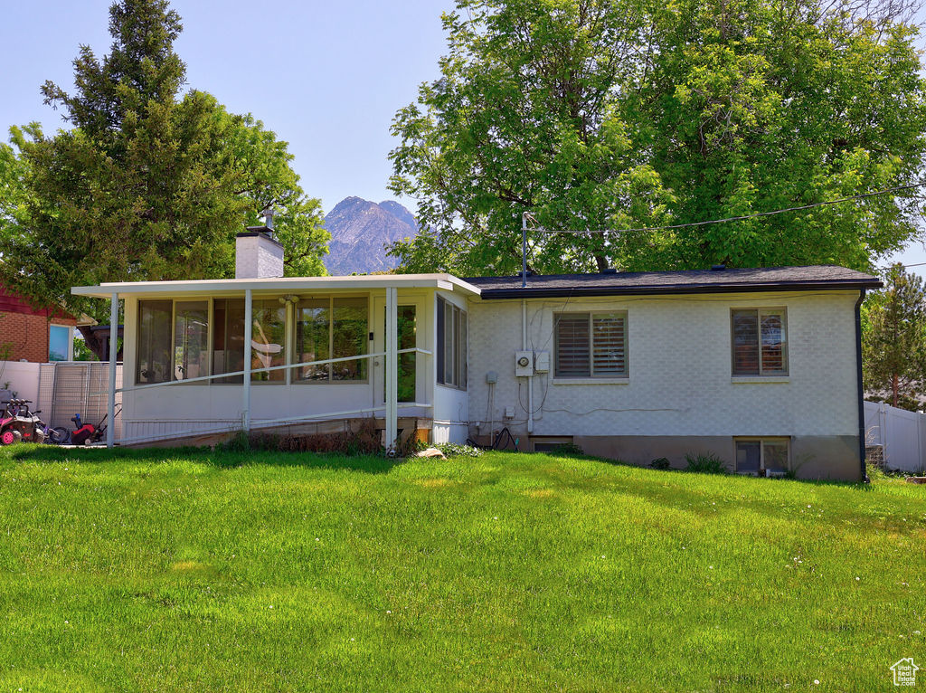 View of front of house with a sunroom, a chimney, and a mountain view