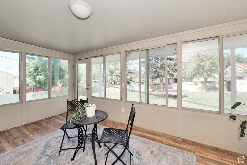 Sunroom / solarium featuring wood finished floors, plenty of natural light, and a deck