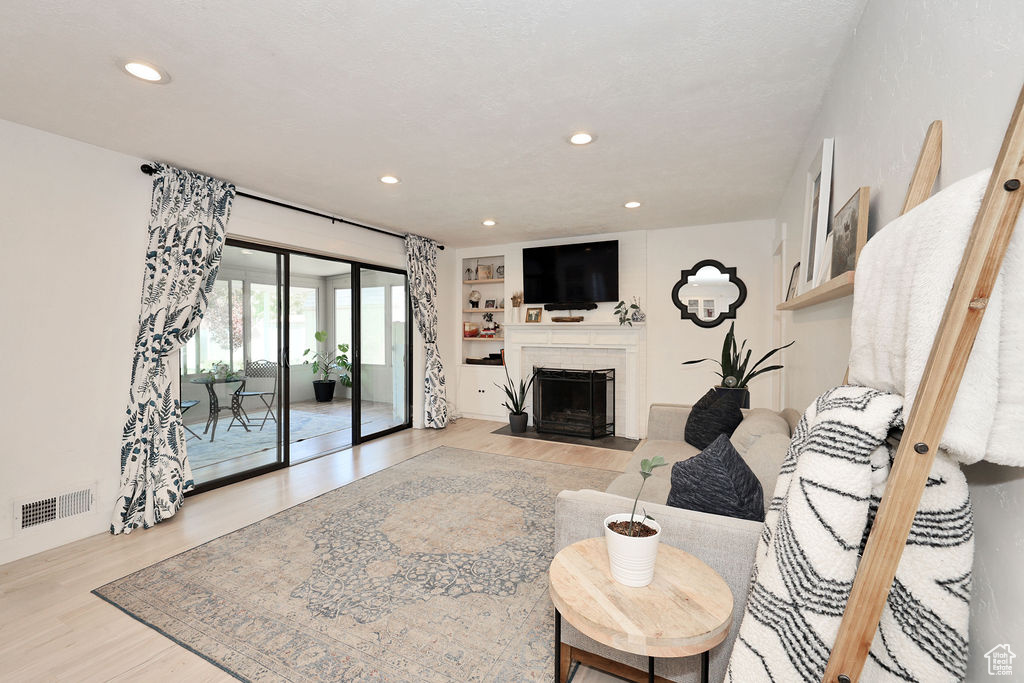 Living area featuring light wood-type flooring, a fireplace with flush hearth, and recessed lighting
