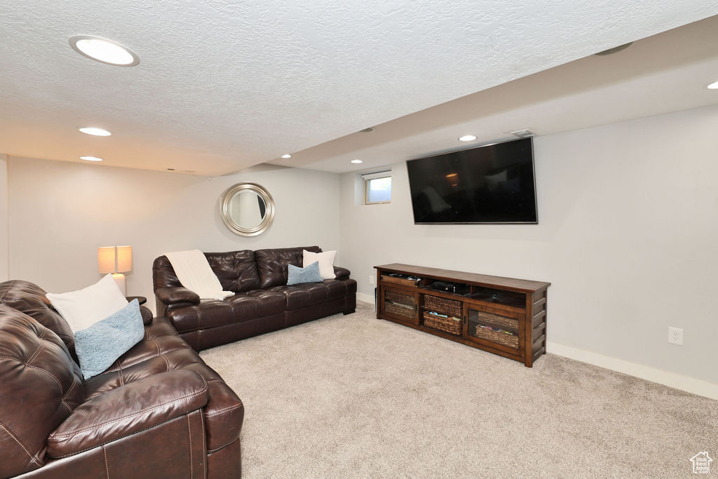 Carpeted living area featuring recessed lighting, a textured ceiling, and baseboards
