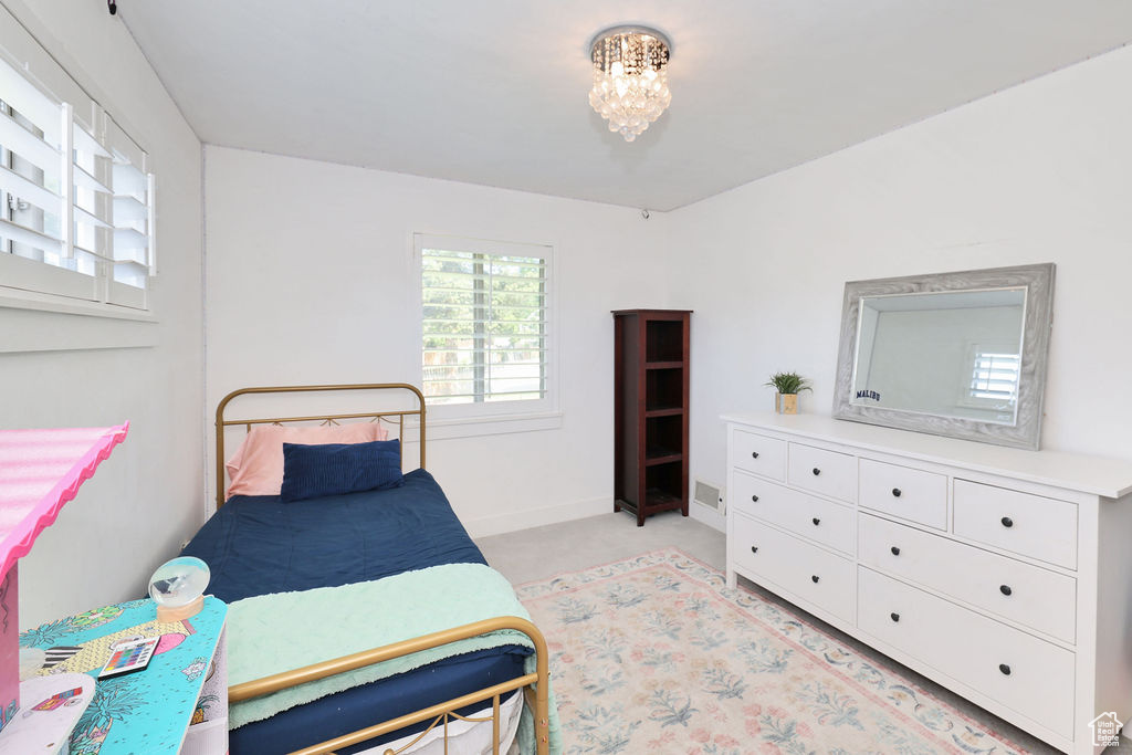Bedroom featuring light carpet, a chandelier, and baseboards