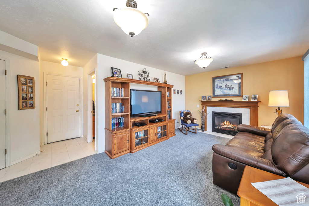 Living room featuring a tile fireplace, carpet, baseboards, and tile patterned floors