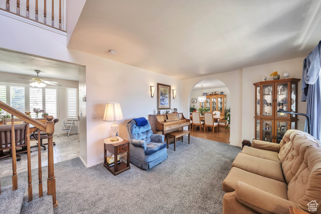 Living room featuring arched walkways, carpet floors, a ceiling fan, and baseboards