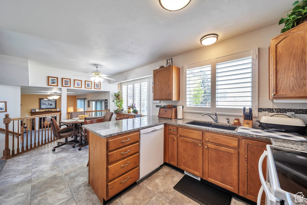 Kitchen featuring white appliances, a sink, a peninsula, brown cabinets, and a ceiling fan