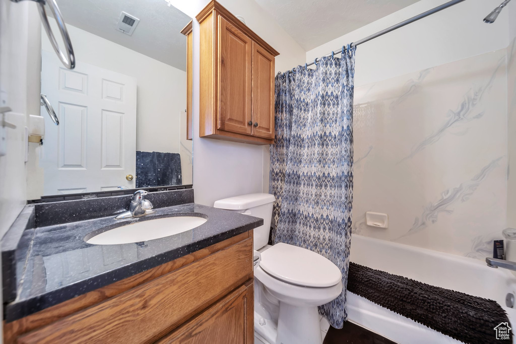 Full bathroom featuring toilet, vanity, and shower / bath combination with curtain