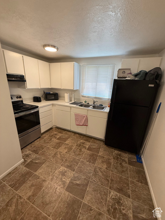 Kitchen with electric range, a textured ceiling, under cabinet range hood, light countertops, and a sink
