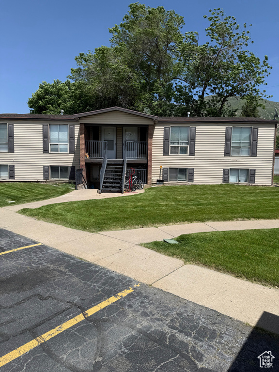 View of front facade with stairs, uncovered parking, a front lawn, and covered porch