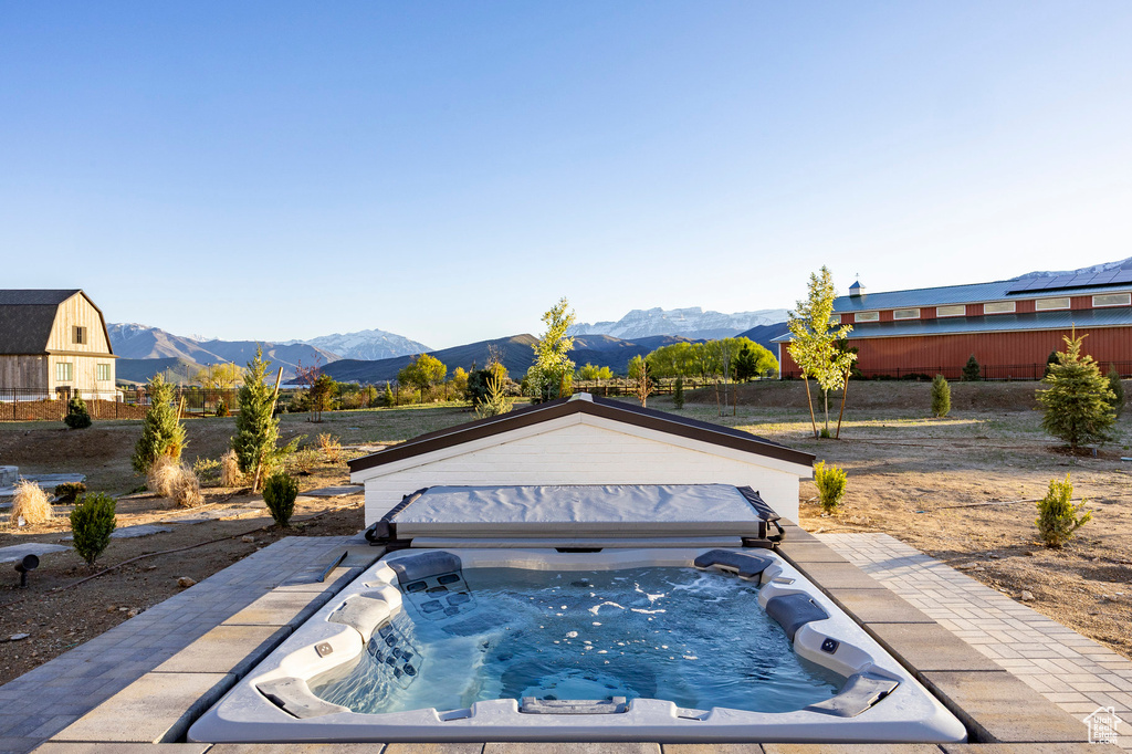 View of swimming pool with a mountain view and a covered hot tub