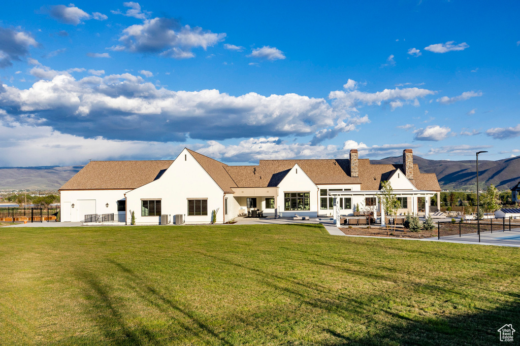 Back of house with a chimney, stucco siding, a patio area, and a mountain view