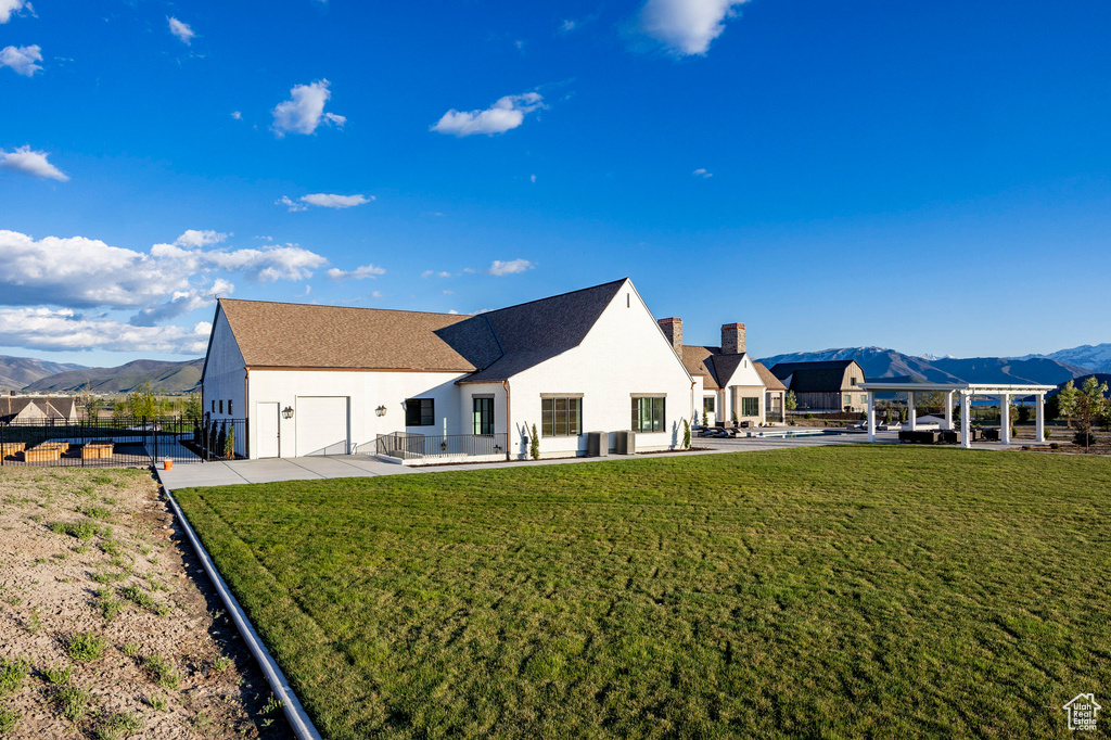 Back of house featuring stucco siding, a mountain view, an attached garage, a chimney, and concrete driveway