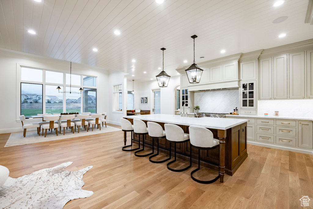 Kitchen with light countertops, light wood-style floors, a kitchen island with sink, wooden ceiling, and recessed lighting