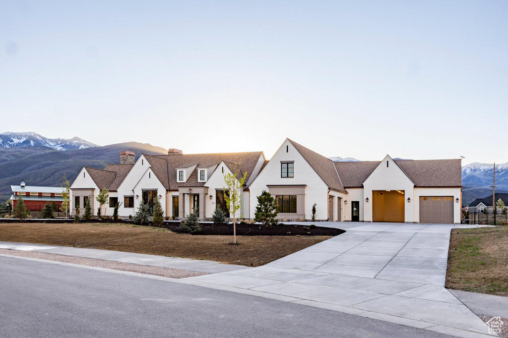 Modern inspired farmhouse featuring a mountain view, stucco siding, a garage, a chimney, and driveway