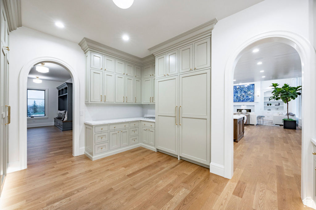 Hall with arched walkways, light wood finished floors, recessed lighting, and baseboards