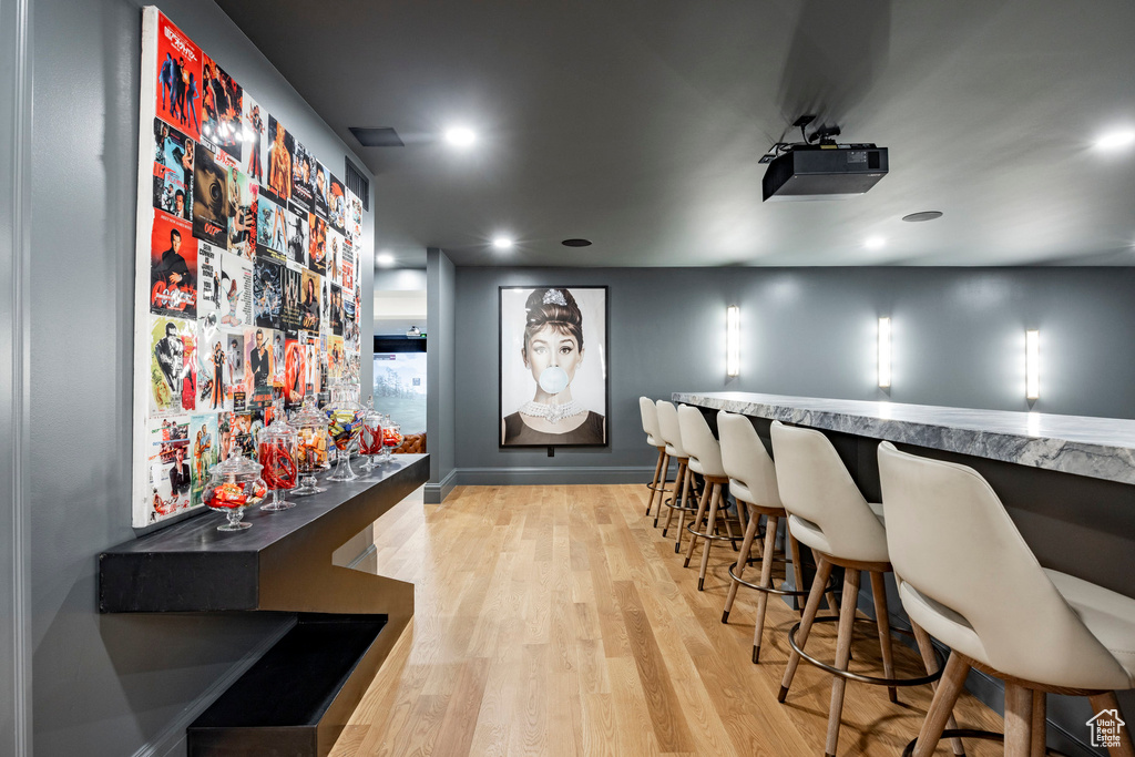 Community bar area with light wood-type flooring, recessed lighting, and baseboards