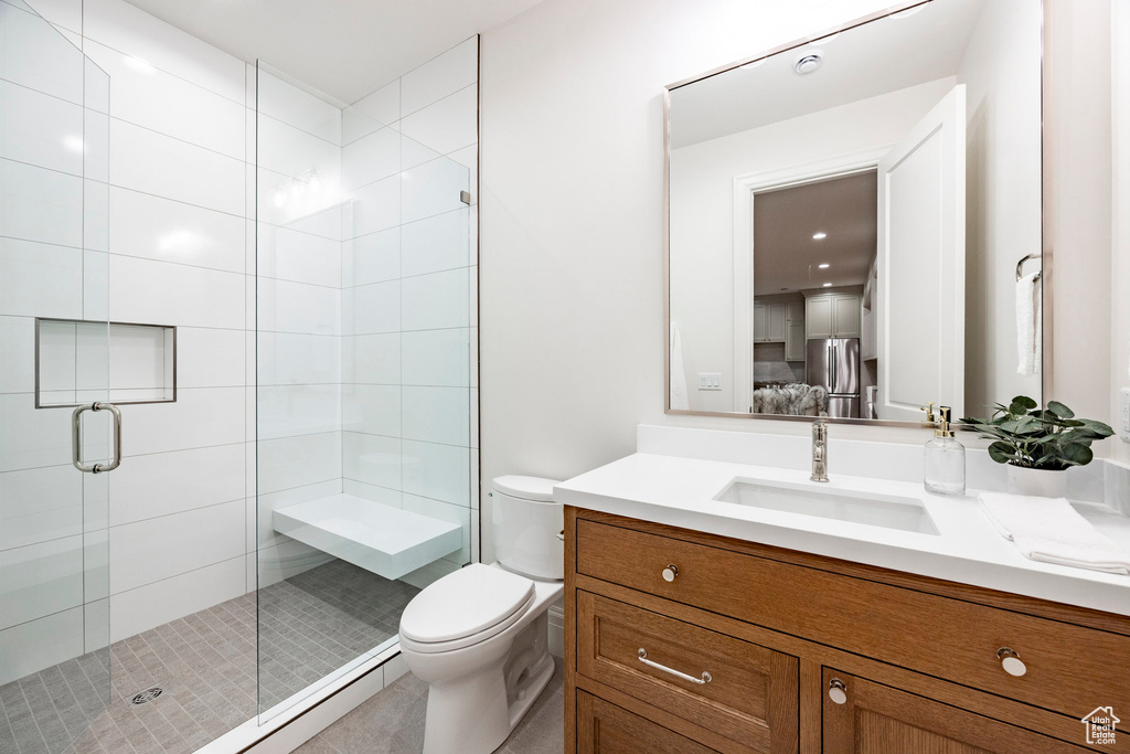 Bathroom featuring a shower stall, toilet, and vanity