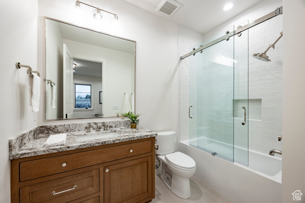 Bathroom featuring vanity, toilet, combined bath / shower with glass door, and tile patterned floors
