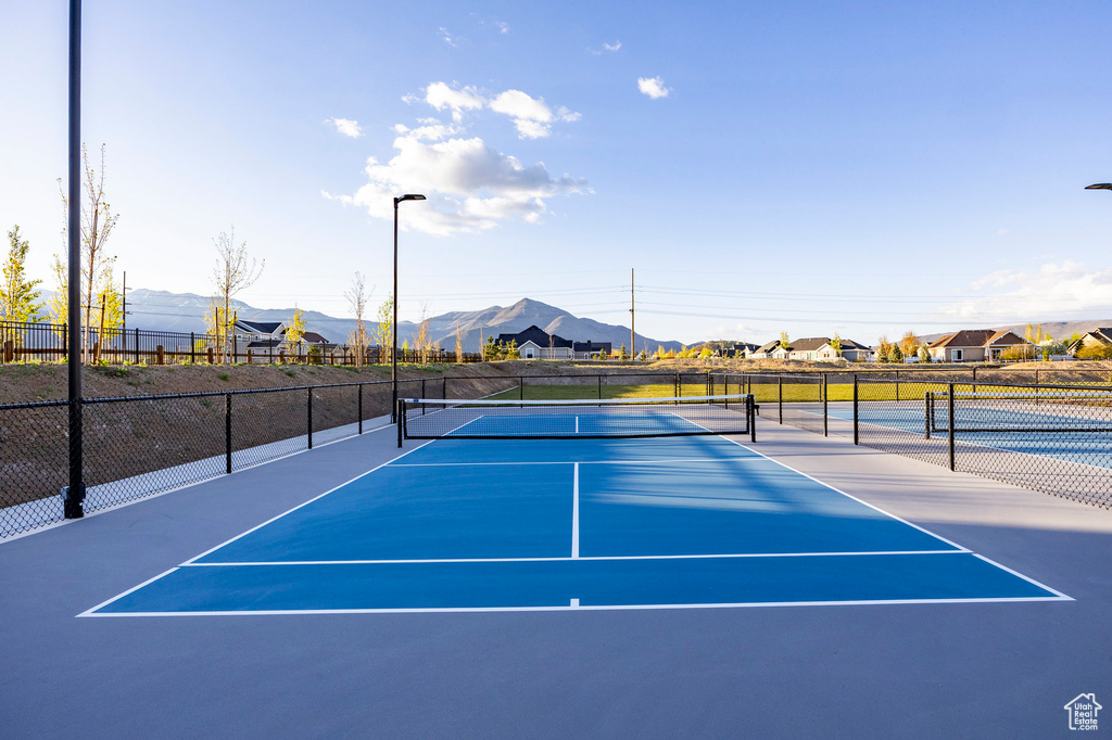 View of tennis court with a mountain view and fence
