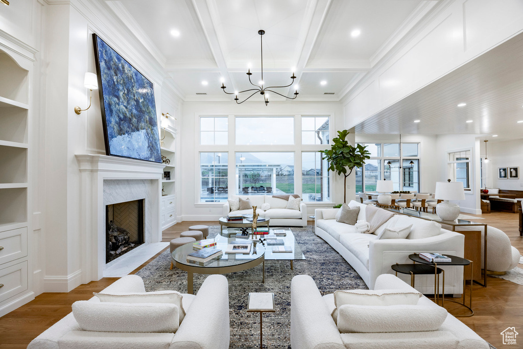 Living room featuring a chandelier, built in features, wood finished floors, coffered ceiling, and beamed ceiling