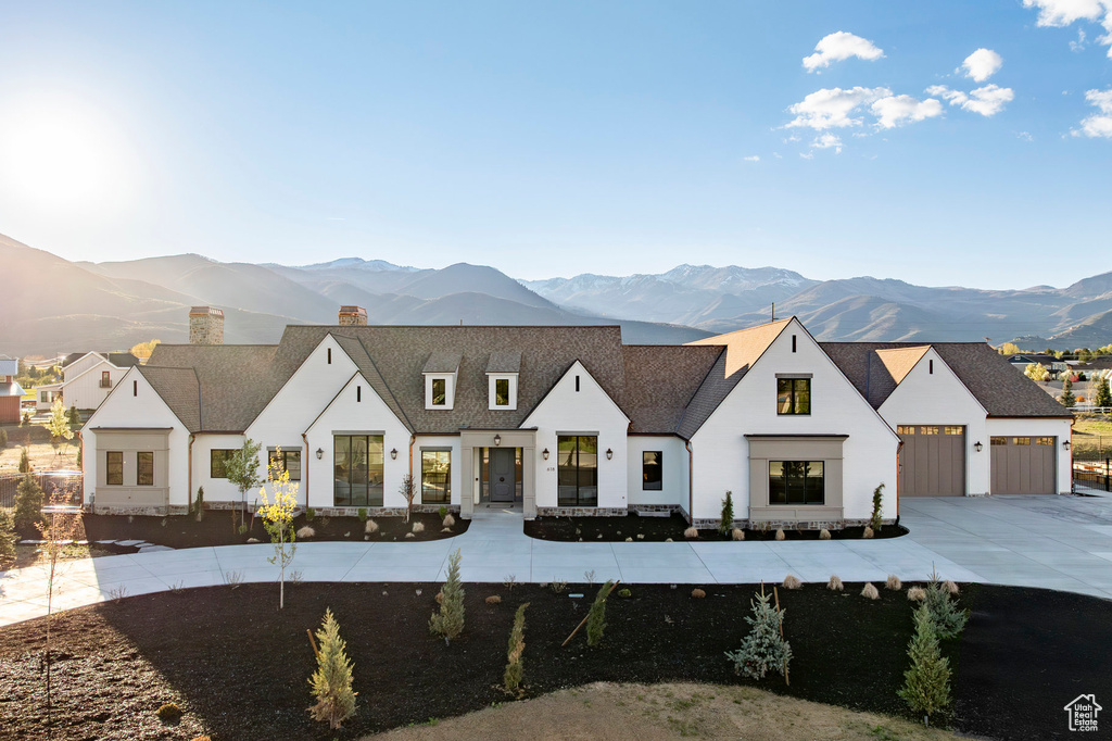 Modern inspired farmhouse with a mountain view, a chimney, concrete driveway, a garage, and a shingled roof