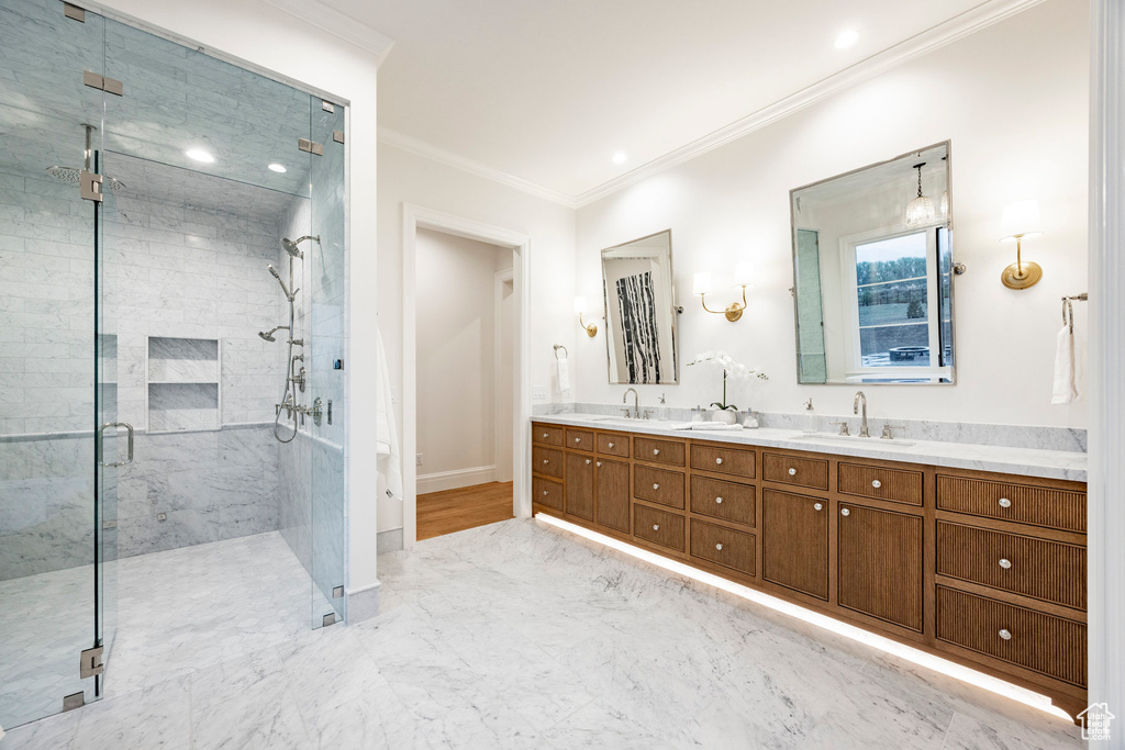 Bathroom with crown molding, marble finish floors, a stall shower, double vanity, and baseboards