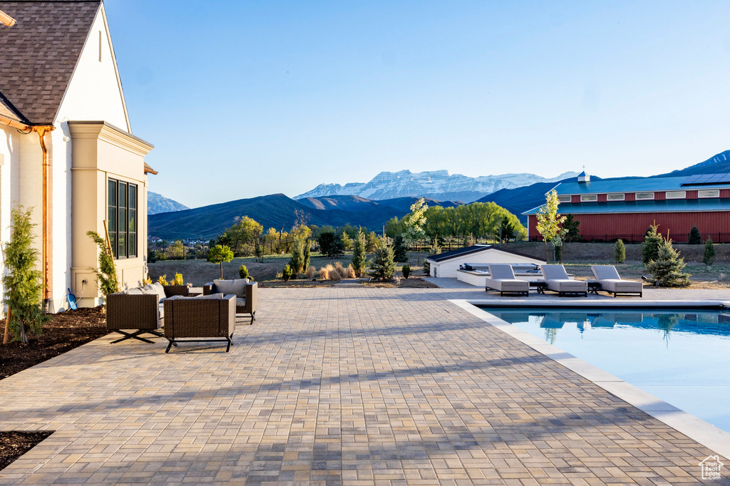 Swimming pool featuring a mountain view, an outdoor living space, and a patio