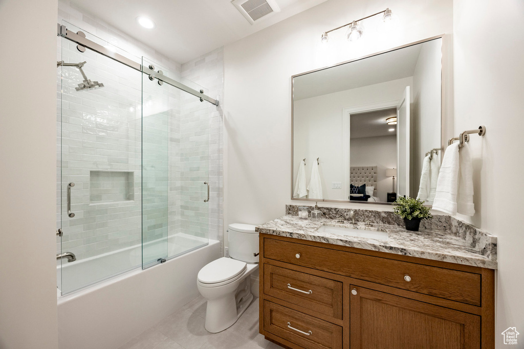 Full bathroom featuring toilet, vanity, bath / shower combo with glass door, and tile patterned floors