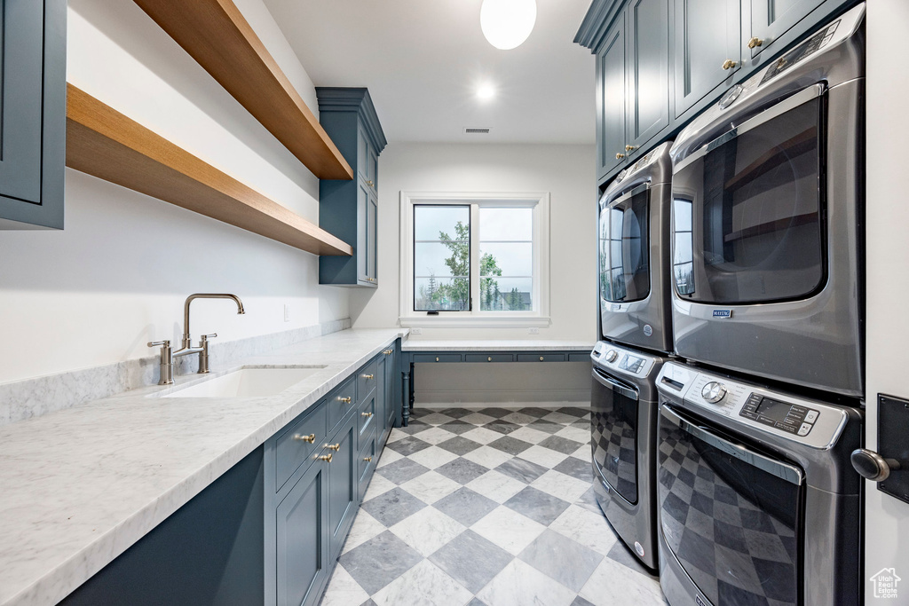 Laundry area featuring stacked washer and clothes dryer, cabinet space, and light flooring