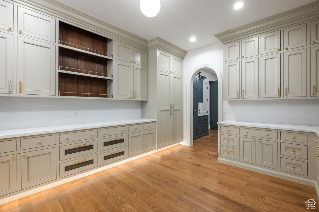 Kitchen with arched walkways, light wood-style floors, open shelves, recessed lighting, and gray cabinetry