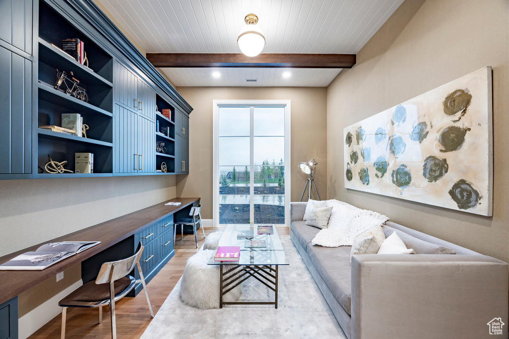 Office space featuring built in study area, light wood-style flooring, beamed ceiling, and baseboards