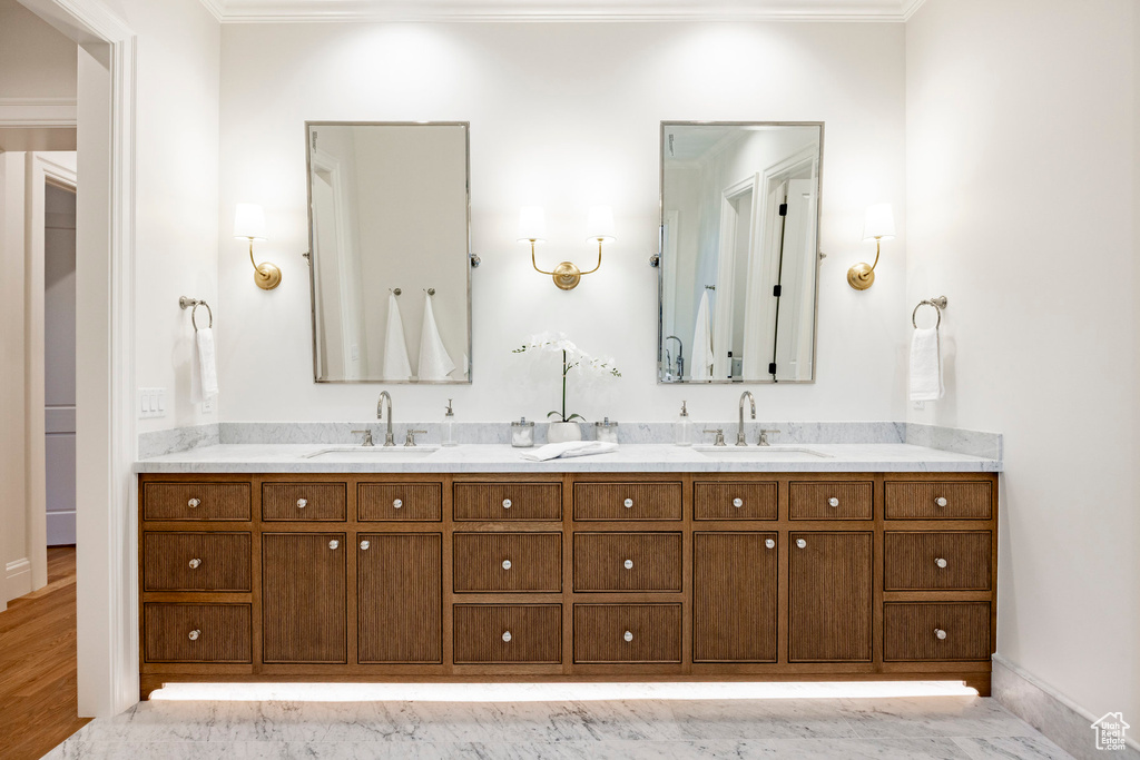 Full bathroom featuring crown molding, double vanity, and baseboards