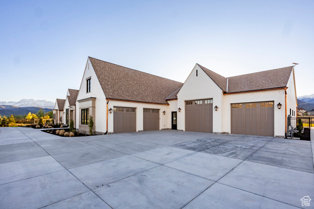 View of property exterior with a garage, driveway, a shingled roof, and a mountain view