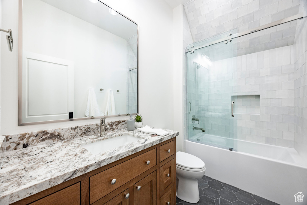 Bathroom with toilet, tile patterned flooring, vanity, and enclosed tub / shower combo