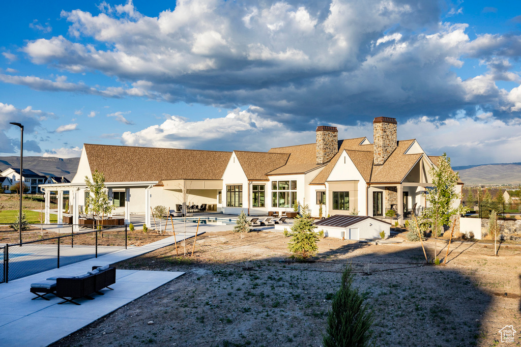 Back of property featuring a chimney, a patio area, stucco siding, and roof with shingles